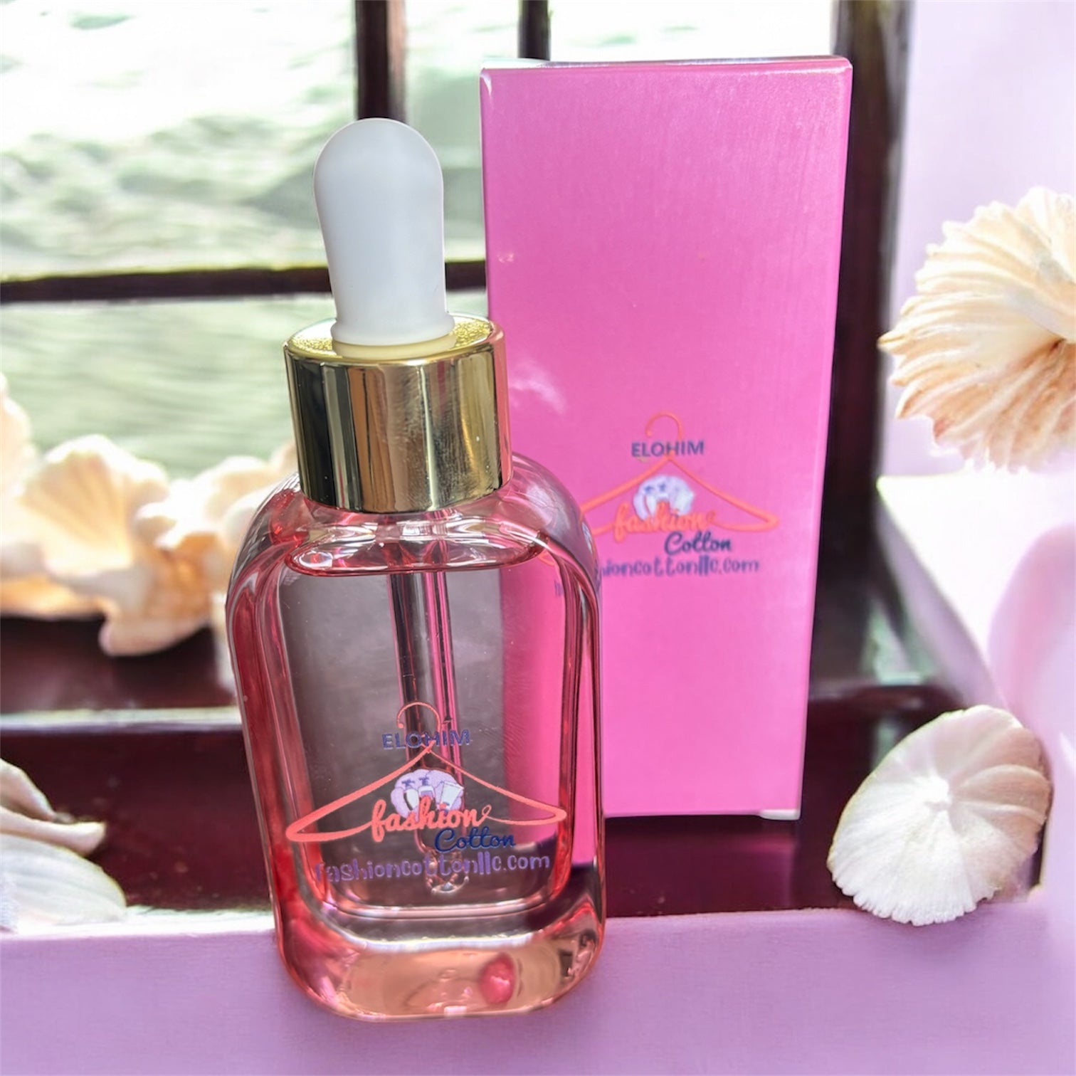 Glass dropper bottle with gold cap on a pink surface, with a pink box in the background.